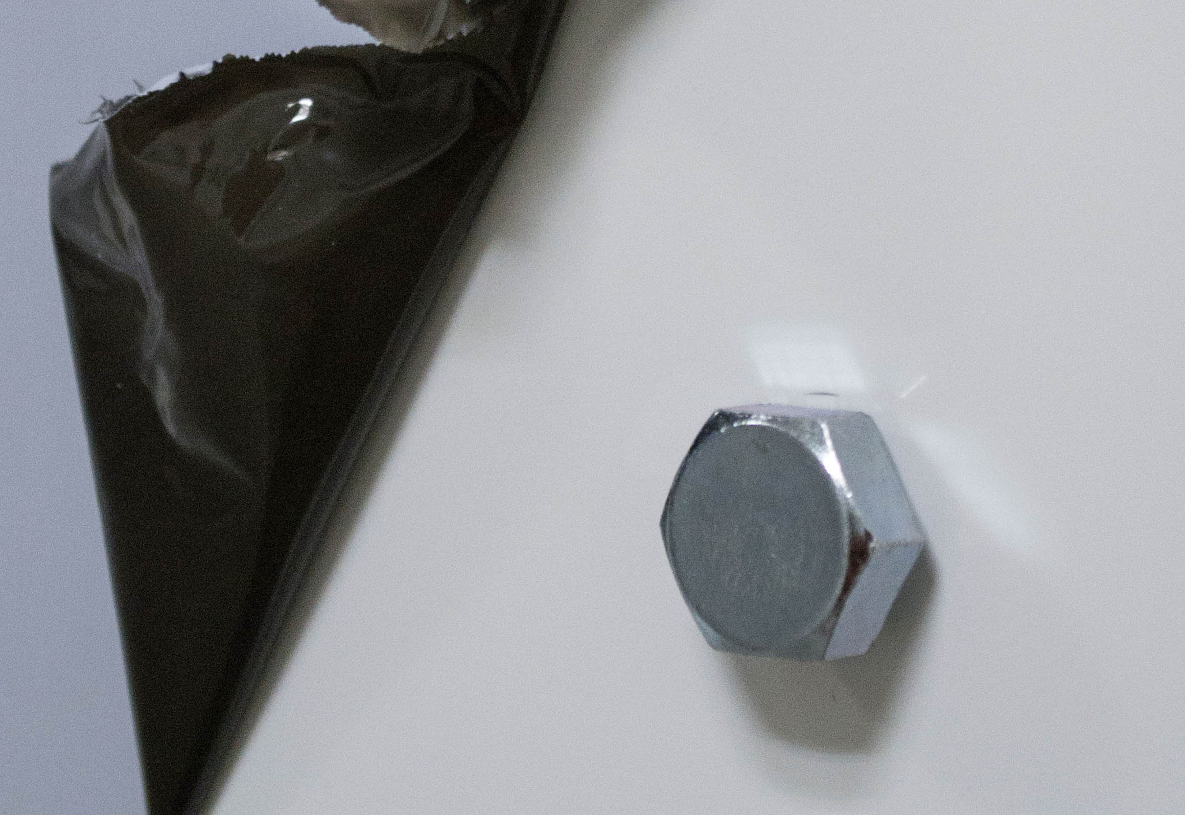 Retained Obstruction No.1, 2014 125 x 125 cm Dibond, Pulled off plastic protector, 3 hexagonal M10 screws, 1 3D printed hexagonal M10 screw, remains of wall dus